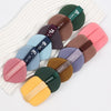 A set of ten air cushion beauty puffs in various shades of pink, green, brown, and blue arranged on a white striped cloth.