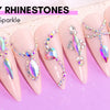 A display of long, pink acrylic nails decorated with various sparkling rhinestones and gems for nail art.