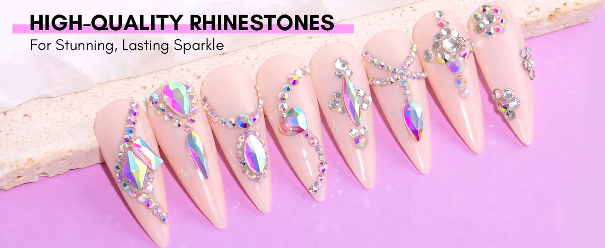 A display of long, pink acrylic nails decorated with various sparkling rhinestones and gems for nail art.