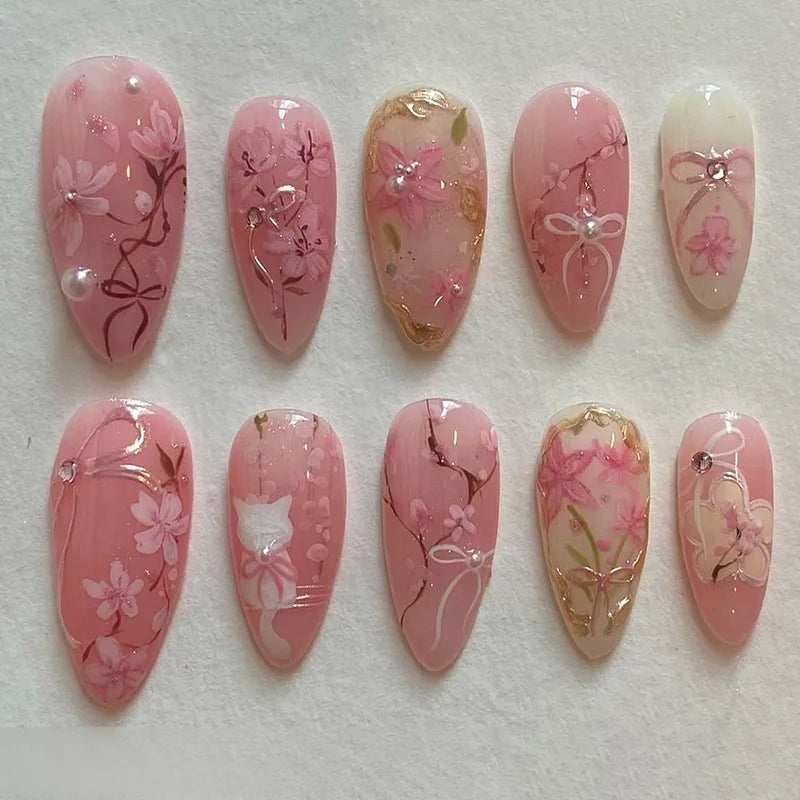 A collection of 24 pink heart pearl press-on fake nails featuring floral designs and glitter accents.