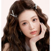 A close-up of a woman with long brown hair styled in waves, holding her hand near her head, featuring a 32MM Waver curling ir