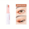 A tube of orange colored eye shadow stick next to a close-up of an eye applying the same shade.
