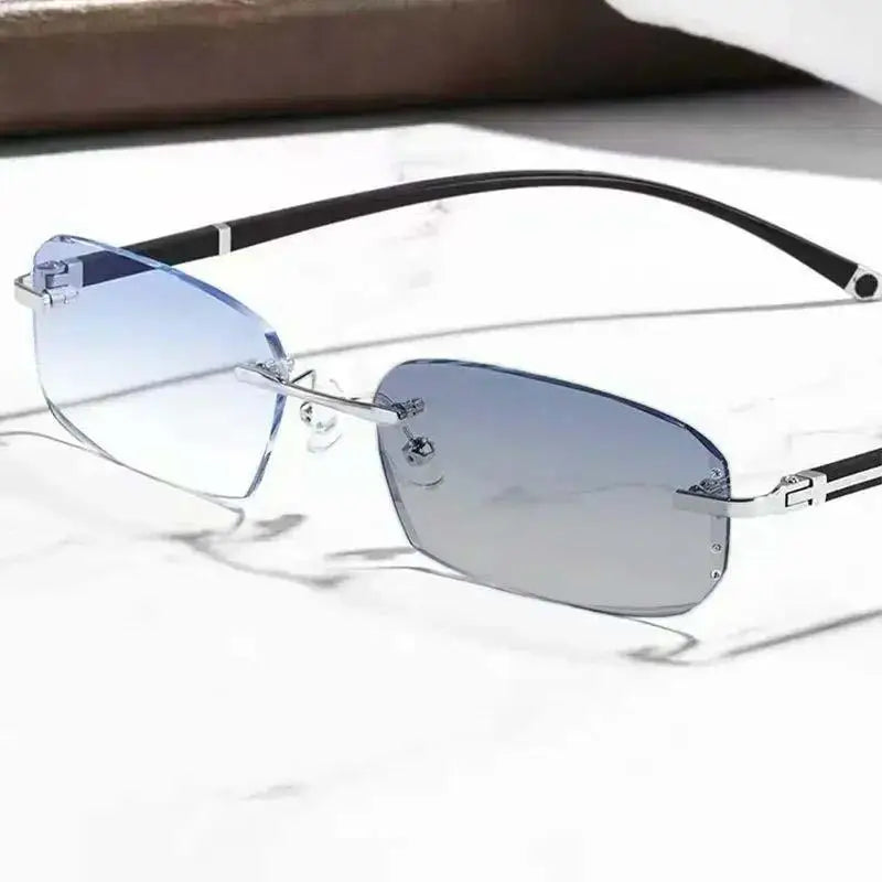 A pair of silver-framed photochromic reading glasses resting on a white marble surface.