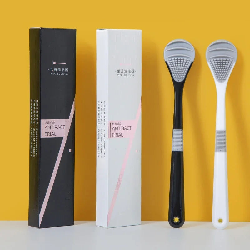 A set of reusable tongue cleaner brushes in black and white packaging displayed against a yellow background.
