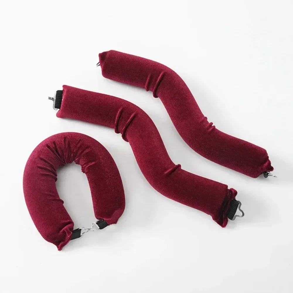 Three maroon heatless hair curler curling rods lying on a white surface.