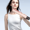 A woman holds a pink hair dryer straightener while wearing a white tank top.