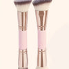 A pair of precision double-ended makeup foundation brushes with pink and rose gold handles and gray bristles.