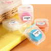 Clear plastic containers holding pink, blue, and orange colored 50m disposable nylon dental floss.