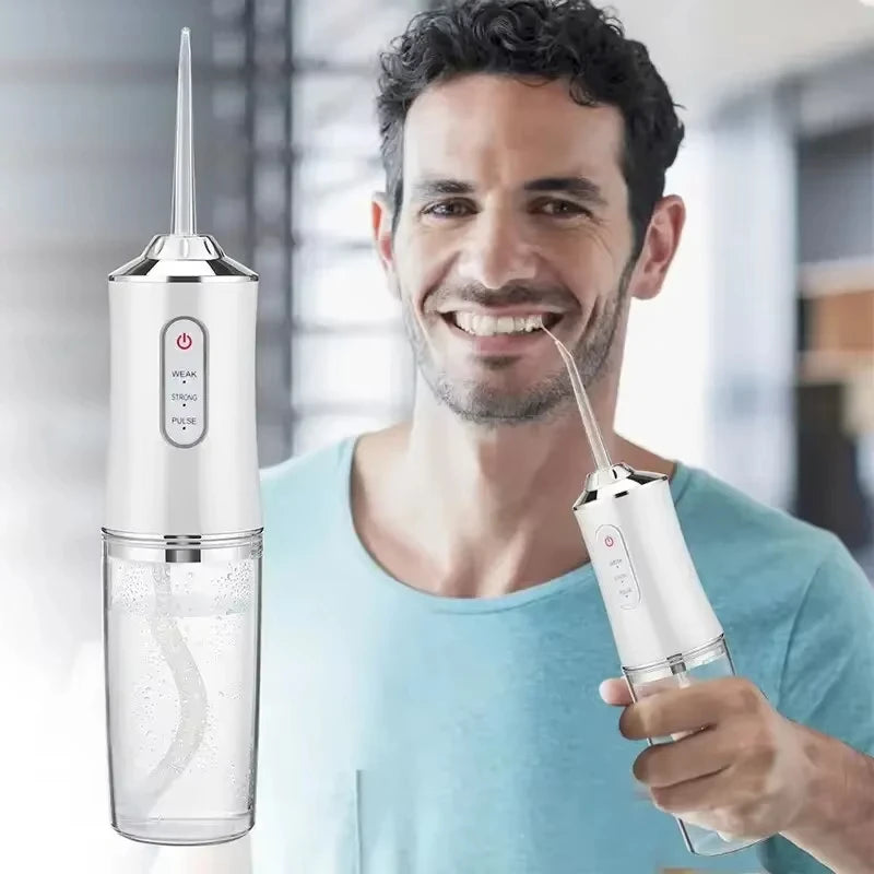 A man holds a portable USB rechargeable water flosser device with a clear water bottle and a detachable tip.