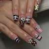 A hand displays press-on nails featuring a French wave design with stars and polka dots in brown, white, and pink tones.