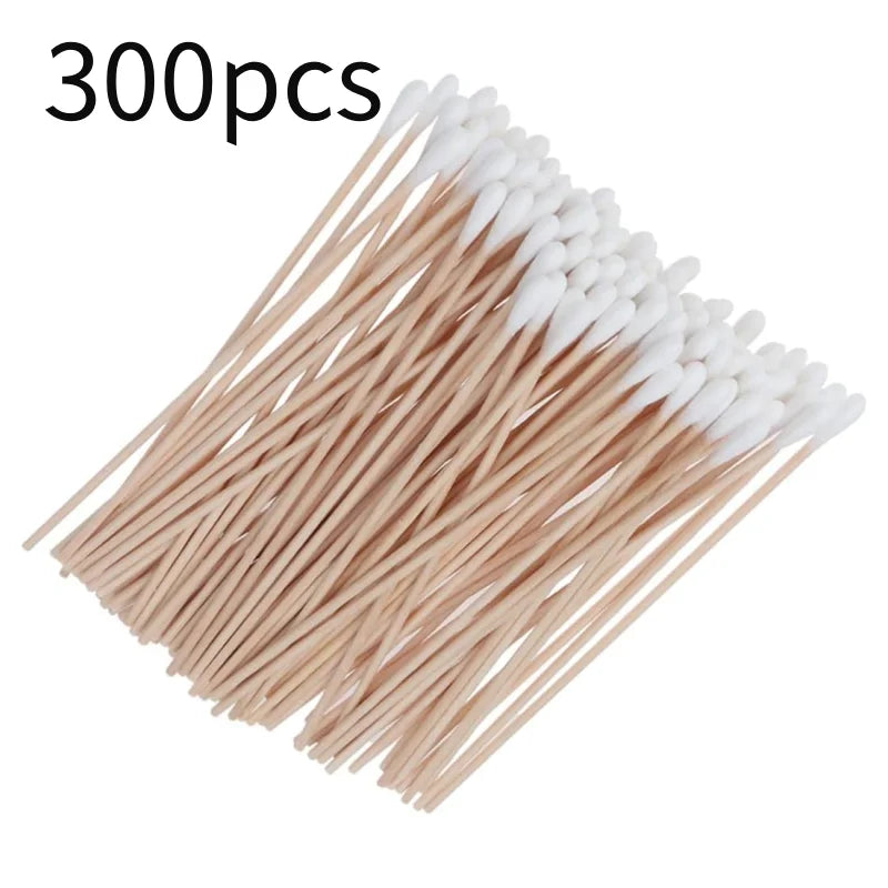 A pile of 300 precision wooden cotton swabs with white tips arranged diagonally.