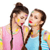 Two women with braided hair are applying colorful face paint to each other.