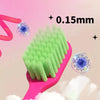 A pink plastic toothbrush with green soft bristles is shown next to a magnified view of the bristles, labeled 0.15mm.