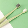 Une paire de brosses à dents vert clair à poils différents est exposée sur un fond vert.