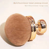 A large, golden-toned multifunctional head makeup brush with a rounded ferrule and dome shape.