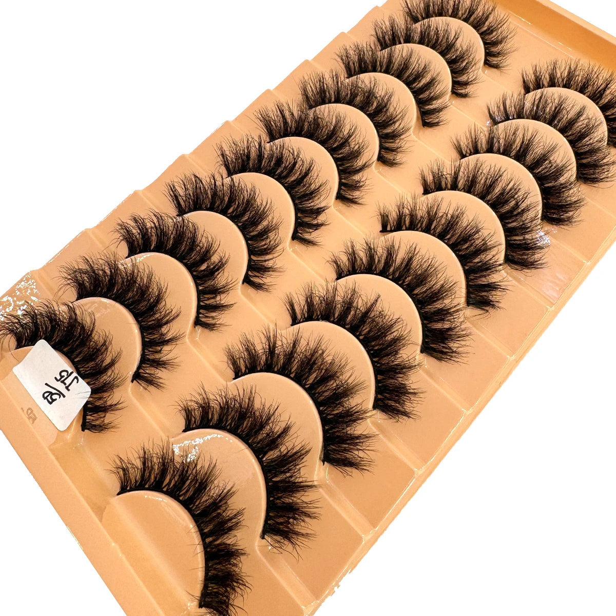 Un plateau de faux cils de renard fabriqués à la main, de divers styles disposés en rangées.