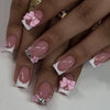 A set of nude pink press-on nails decorated with leopard print accents and 3D floral charms.