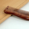 A wooden scalp and hair comb set resting on a light wood surface.