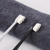 A black toothbrush with white bristles rests on a gray towel.