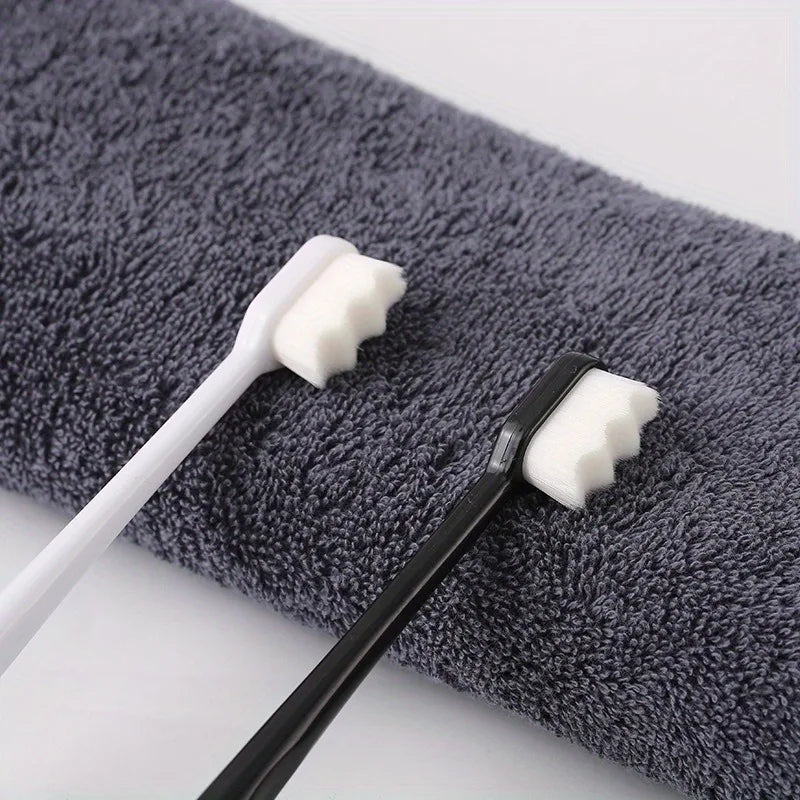A black toothbrush with white bristles rests on a gray towel.
