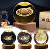 A glass crystal ball showing a galaxy night light effect on a wooden base.