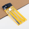 A stainless steel dental cleaning tool set in a yellow plastic case resting on brown cardboard.