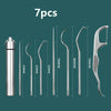 Un set de sept cure-dents et outils de détartrage en acier inoxydable sur fond vert foncé.