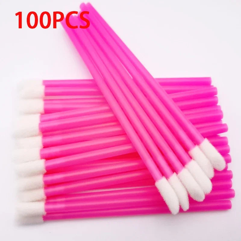 A set of 100 pink precision makeup brushes with white tips laid out on a pink surface.
