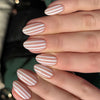Close-up of a hand displaying pink and white striped almond shaped press-on nails