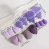 Un ensemble d'éponges de maquillage et d'embouts de poudre à plusieurs faces dans diverses nuances de violet et de lilas, dis