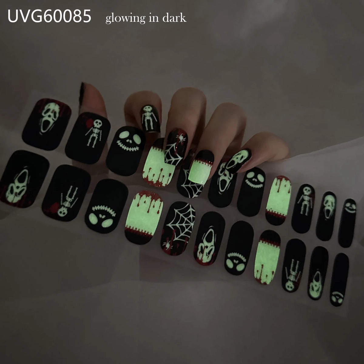 A hand displaying UV gel nail stickers with Halloween themed designs on the fingernails.
