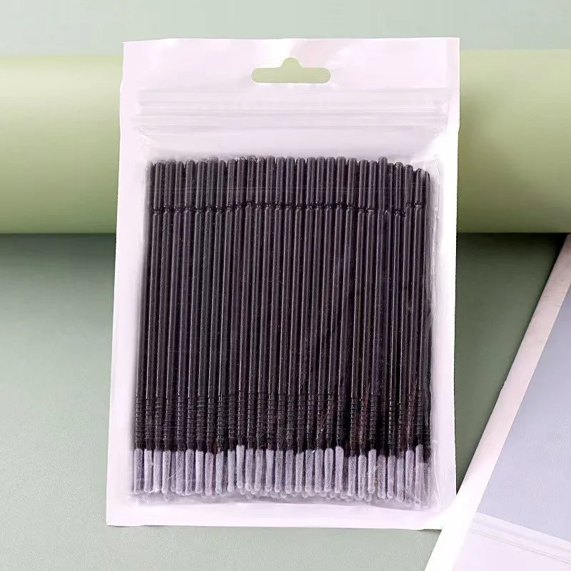 A clear plastic package containing a bundle of black eyelash extension cleaning swabs.