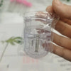 A hand holds a clear plastic mini folding eyelash curler set.
