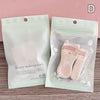 A clear plastic pouch containing pink beauty makeup tools including an eyelash curler and tweezers.