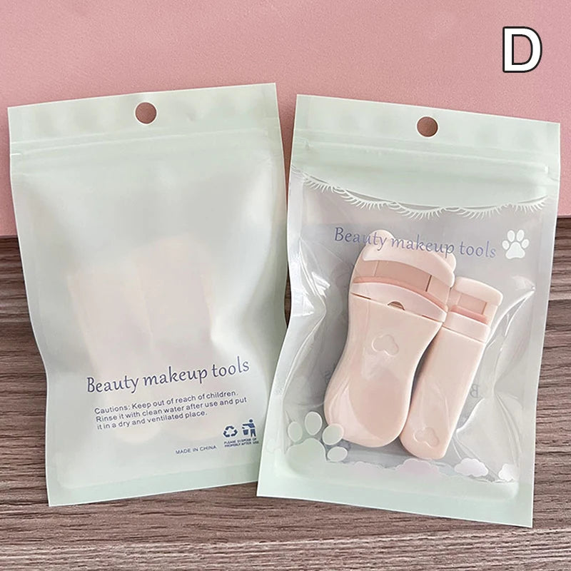 A clear plastic pouch containing pink beauty makeup tools including an eyelash curler and tweezers.