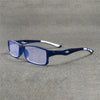 Un par de gafas deportivas azul oscuro anti-luz sobre una superficie gris texturizada.