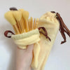 A hand holds a yellow makeup brush set with brown ties and bristles against a white background.