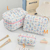 A collection of quilted cotton makeup bags in various floral patterns and colors, including a butter-themed bag.