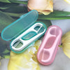 A pink portable teeth flosser cleaning stick set with a white handle is displayed next to yellow and white flowers.