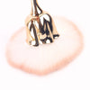 Gold-toned nail art dust brush with a fluffy pink bristles and a metallic gold handle.