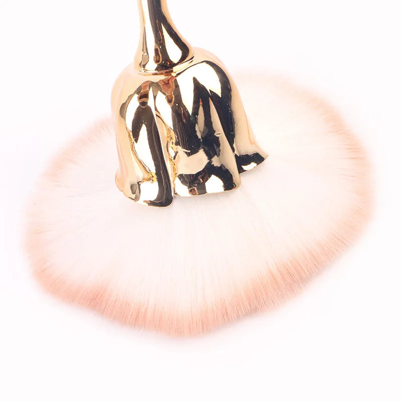 Gold-toned nail art dust brush with a fluffy pink bristles and a metallic gold handle.