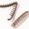 A set of five banana-shaped hair clips in a tan or beige color shown against a white background.