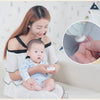A woman gently shows a baby how to use an electric nail trimmer on their finger.