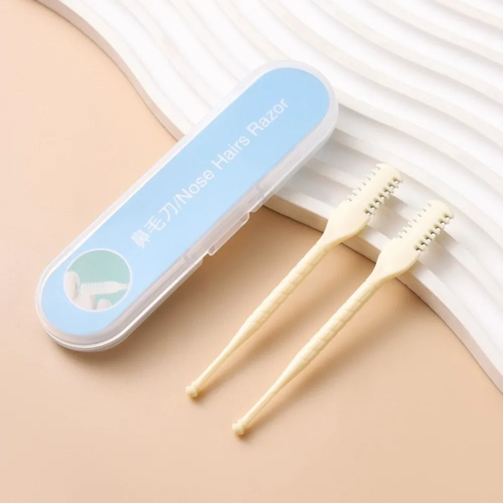 A clear plastic case holds two light beige double-sided nose hair razors resting on a beige surface.