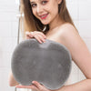 A woman holds a gray non-slip shower foot scrubber mat for exfoliation.
