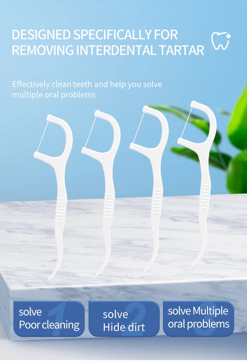 White reusable dental flossers and plastic toothpicks displayed on a white marble surface.
