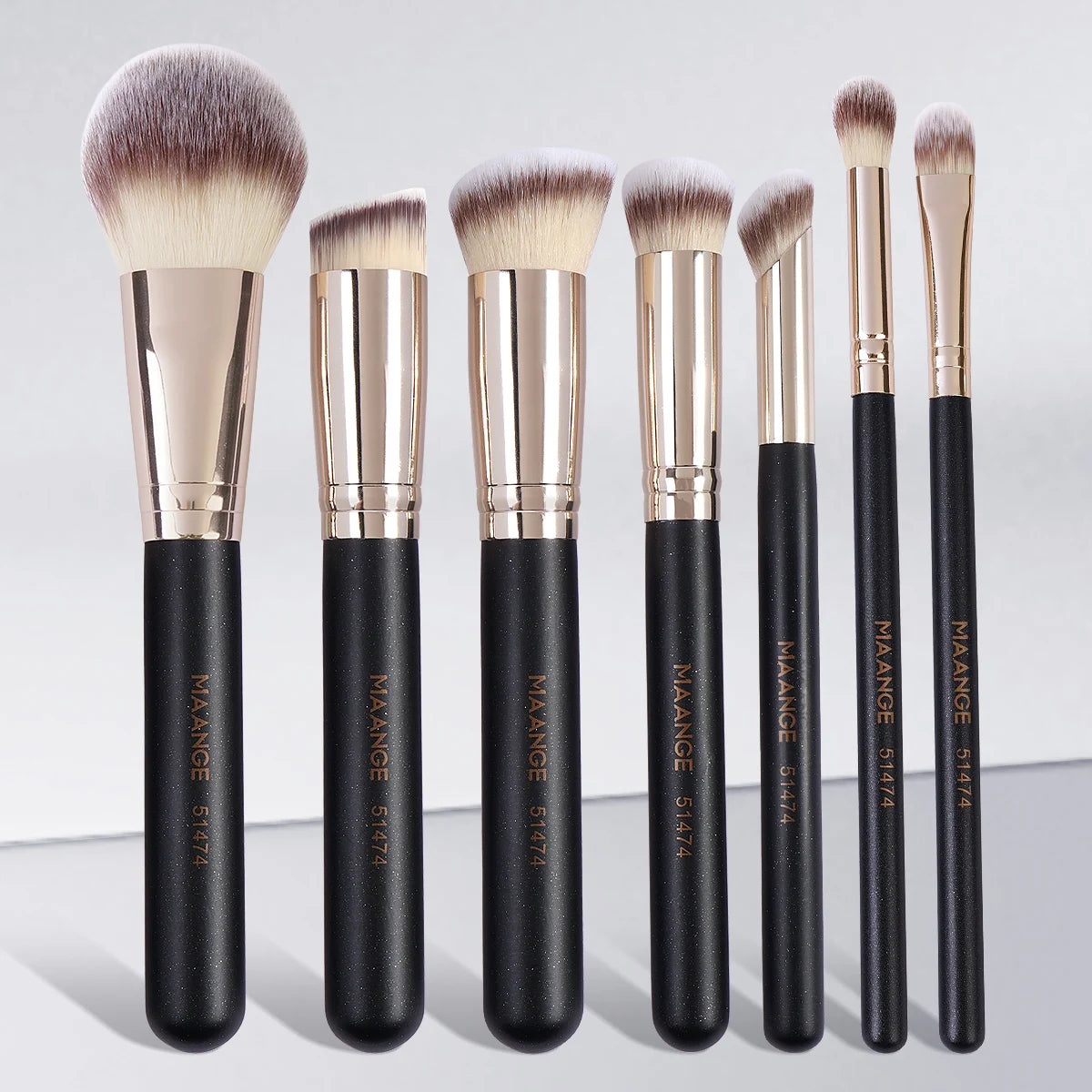 A set of seven professional makeup brushes with gold ferrules and black handles displayed vertically.