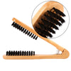 A wooden double-sided hair comb with black bristles shown in a close-up view.