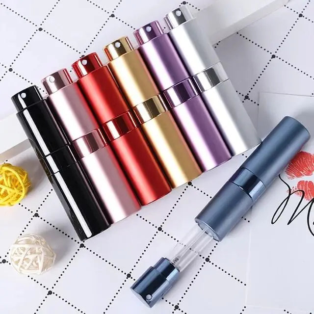 Un ensemble d'atomiseurs de parfum multifonctionnels de différentes couleurs métalliques, disposés sur une surface blanche.