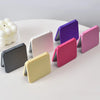A collection of double-sided portable makeup mirrors in various colors, including purple, pink, green, and gray.